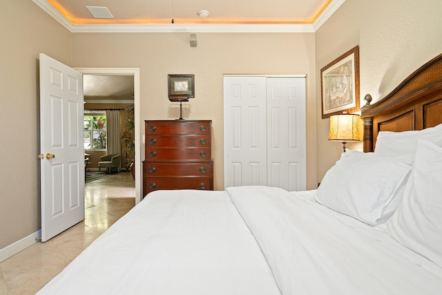 bedroom with a closet, light tile patterned flooring, a textured ceiling, and ornamental molding