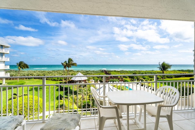 balcony with a water view and a view of the beach