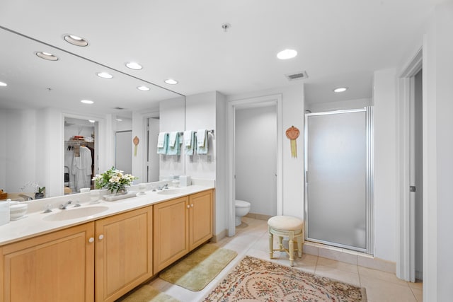 bathroom featuring tile patterned flooring, vanity, toilet, and a shower with door