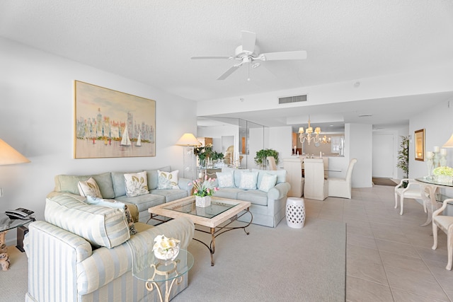 tiled living room with a textured ceiling and ceiling fan with notable chandelier