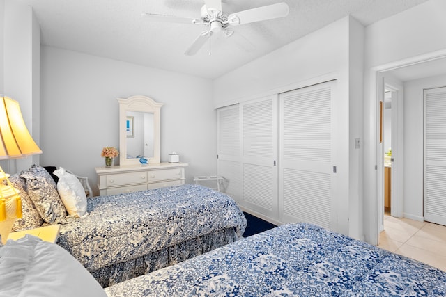 tiled bedroom with ceiling fan, a textured ceiling, and a closet