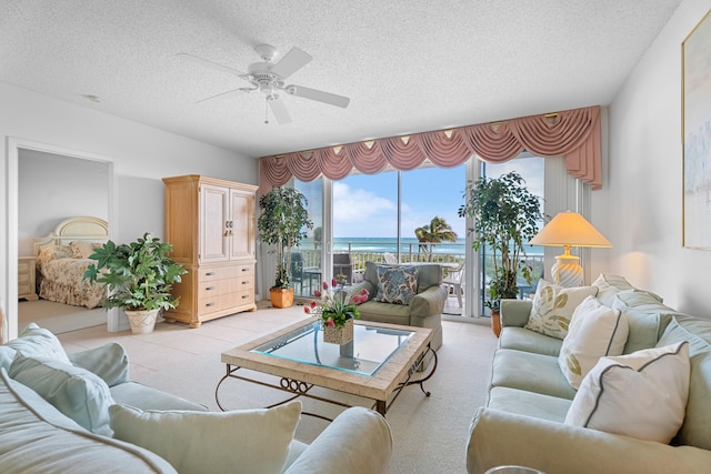 carpeted living room featuring ceiling fan, a water view, and a textured ceiling