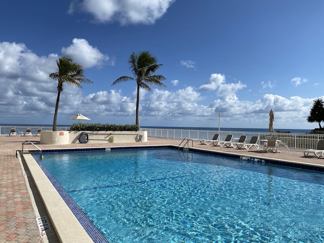 view of pool with a water view and a patio