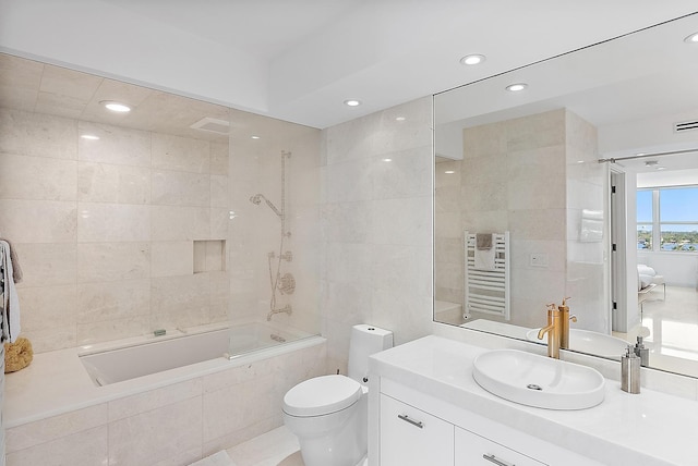 full bathroom with vanity, tiled shower / bath combo, toilet, tile walls, and radiator heating unit