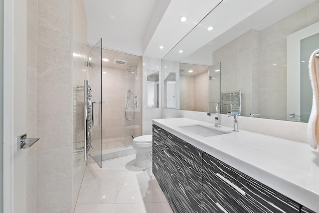 bathroom featuring tile patterned flooring, a tile shower, vanity, and toilet