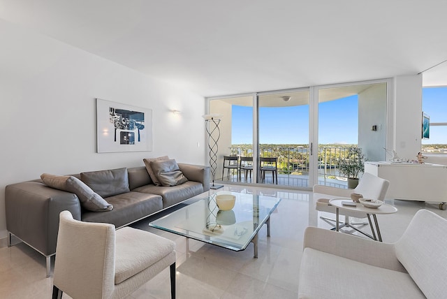 living room with plenty of natural light, a water view, and a wall of windows