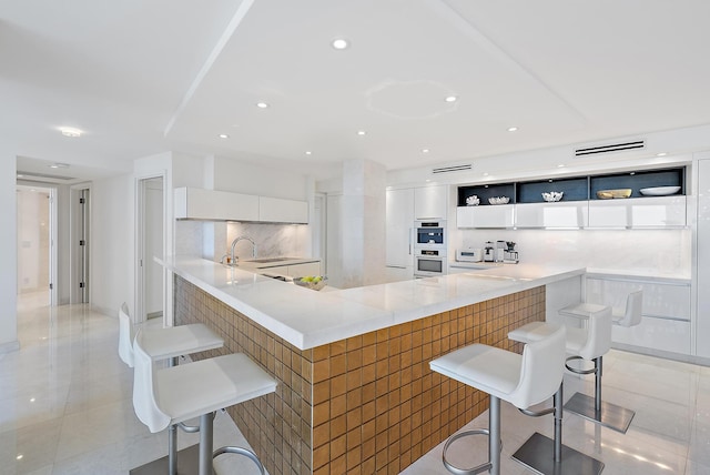 kitchen with backsplash, kitchen peninsula, white cabinetry, and a breakfast bar