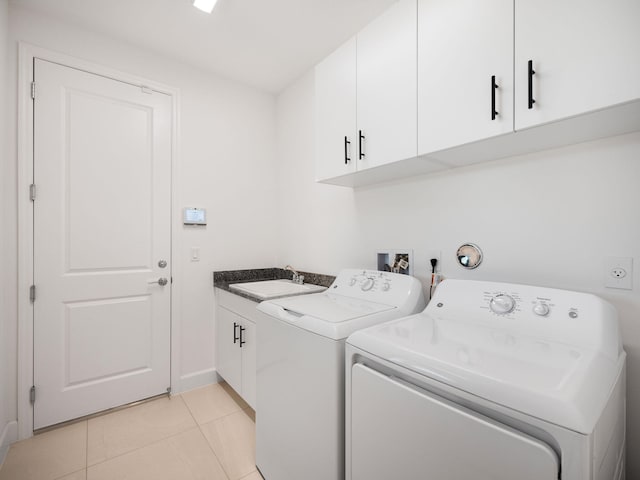 laundry area featuring washer and clothes dryer, sink, light tile patterned floors, and cabinets