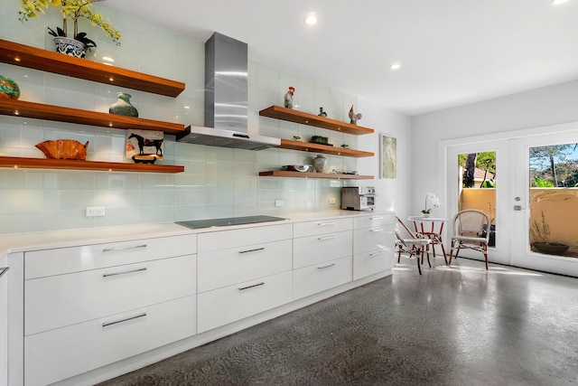 kitchen with backsplash, white cabinets, black electric stovetop, and wall chimney range hood