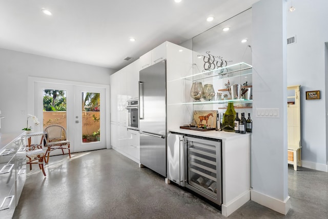 interior space with beverage cooler, white cabinetry, appliances with stainless steel finishes, and french doors