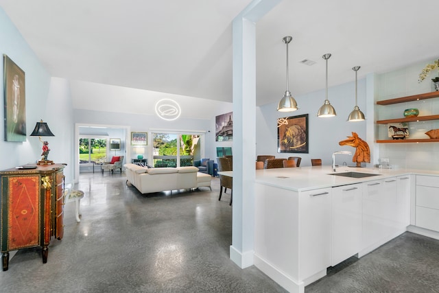 kitchen with kitchen peninsula, pendant lighting, white cabinetry, and sink