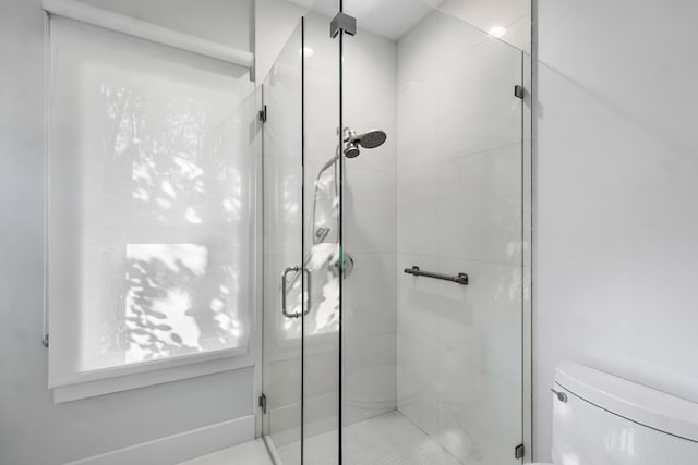 bathroom featuring walk in shower and toilet