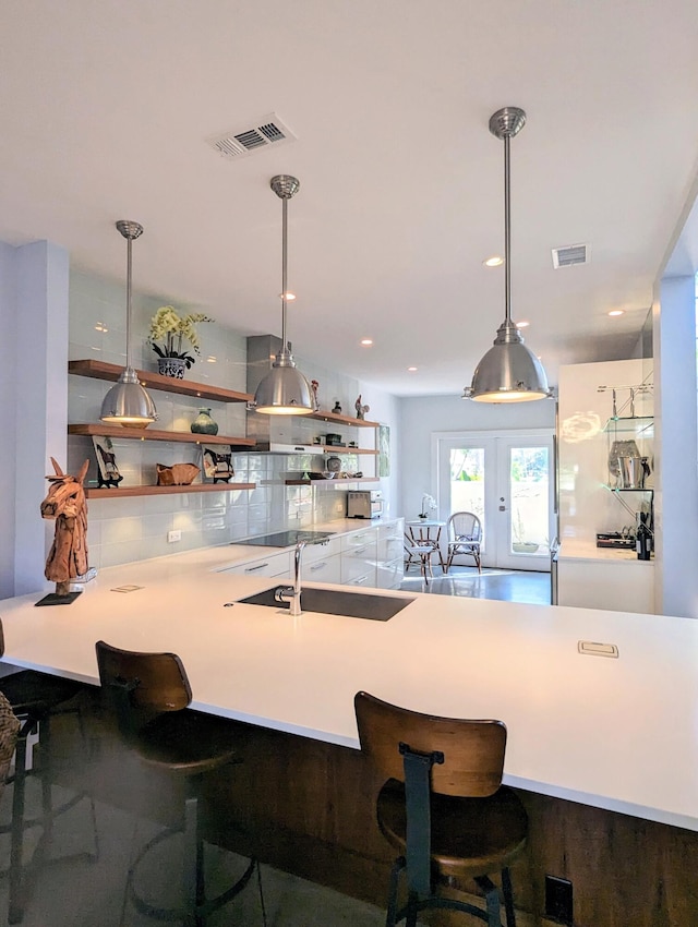 kitchen with sink, french doors, hanging light fixtures, tasteful backsplash, and wood-type flooring