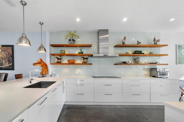 kitchen with pendant lighting, sink, wall chimney range hood, and white cabinets