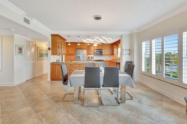 dining room featuring light tile patterned floors, a textured ceiling, and ornamental molding