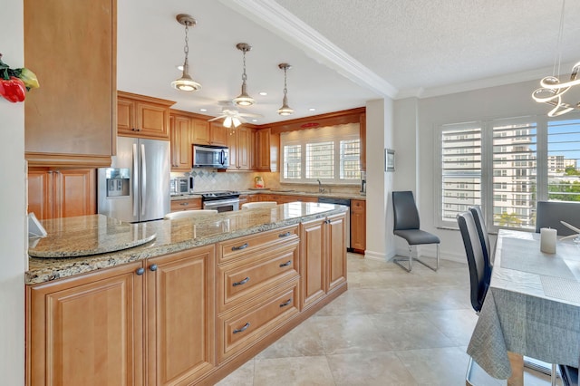 kitchen featuring appliances with stainless steel finishes, a textured ceiling, light stone counters, and hanging light fixtures