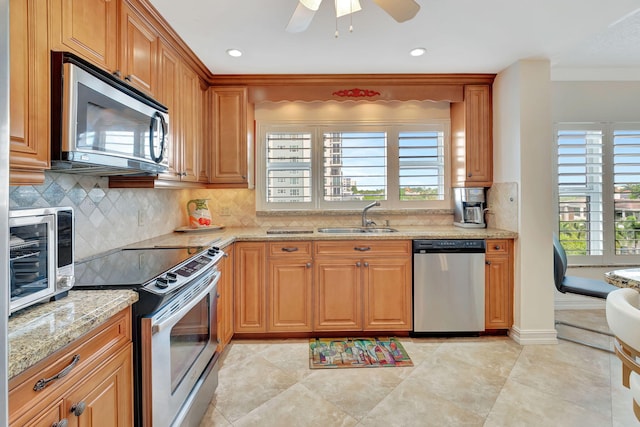 kitchen with backsplash, light stone counters, sink, and stainless steel appliances