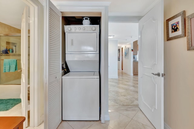 clothes washing area featuring light tile patterned floors, stacked washing maching and dryer, and ornamental molding