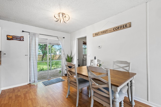 dining room featuring a textured ceiling, baseboards, and wood finished floors