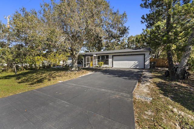 view of front facade featuring a garage, a front yard, driveway, and fence