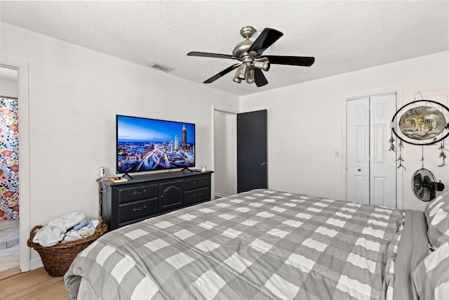 bedroom with a closet, visible vents, ceiling fan, a textured ceiling, and wood finished floors