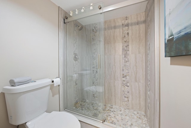 bathroom featuring a shower with shower door and toilet