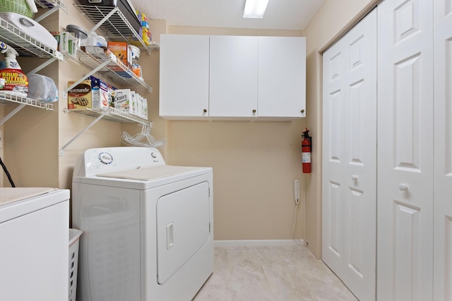 laundry room featuring separate washer and dryer, cabinets, and a textured ceiling