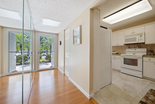 kitchen with white cabinets, a textured ceiling, and white appliances