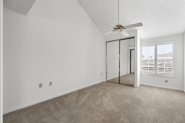 unfurnished bedroom featuring light carpet, vaulted ceiling, ceiling fan, a textured ceiling, and a closet