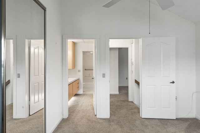 unfurnished bedroom with ensuite bathroom, ceiling fan, light carpet, and vaulted ceiling