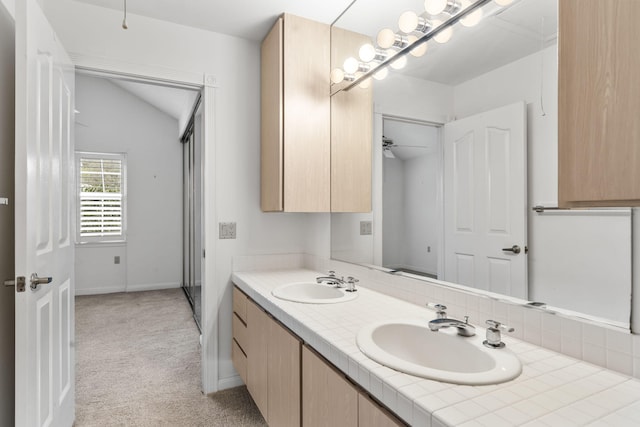 bathroom with ceiling fan, vanity, and vaulted ceiling