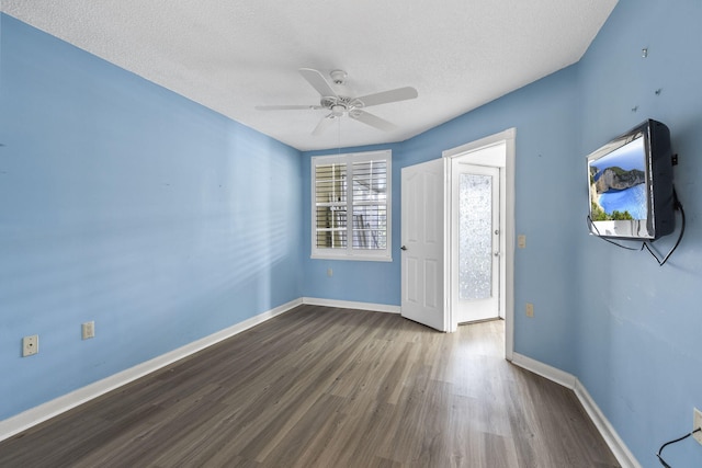 unfurnished room with a textured ceiling, ceiling fan, and dark wood-type flooring