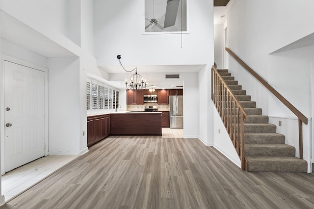 kitchen with decorative backsplash, stainless steel appliances, light hardwood / wood-style flooring, a notable chandelier, and hanging light fixtures