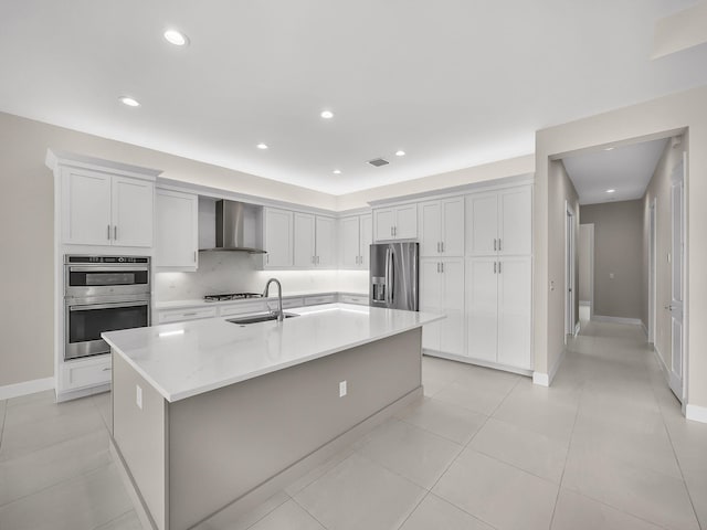11282 SW Sea Cove Ln, Port Saint Lucie, FL 34987 - kitchen featuring wall chimney range hood, stainless steel appliances, a sink, a large island, and white cabinetry