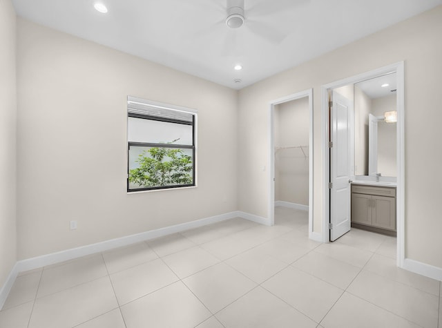 11282 SW Sea Cove Ln, Port Saint Lucie, FL 34987 - unfurnished bedroom featuring a walk in closet, a sink, a closet, ensuite bath, and baseboards
