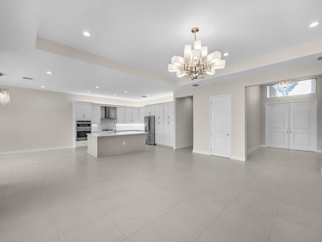 11282 SW Sea Cove Ln, Port Saint Lucie, FL 34987 - unfurnished living room with a chandelier, recessed lighting, a sink, a raised ceiling, and baseboards