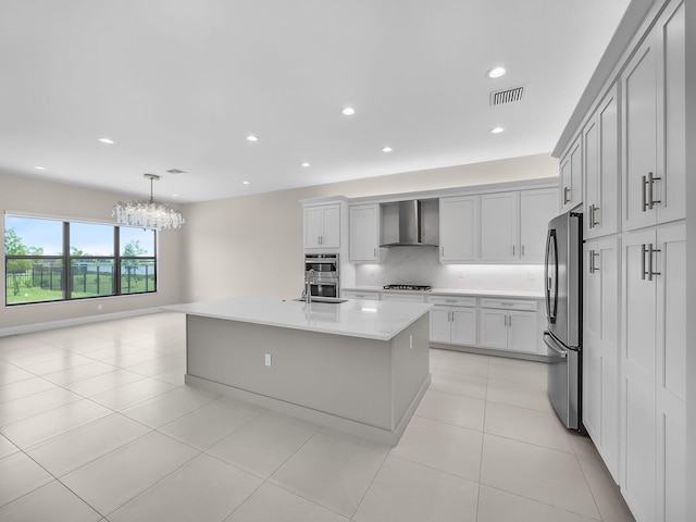 11282 SW Sea Cove Ln, Port Saint Lucie, FL 34987 - kitchen with wall chimney range hood, appliances with stainless steel finishes, a chandelier, light countertops, and a kitchen island with sink
