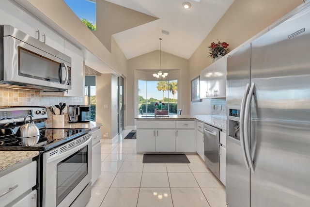 kitchen with white cabinets, decorative backsplash, light tile patterned floors, appliances with stainless steel finishes, and a chandelier