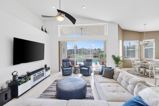 living room featuring ceiling fan with notable chandelier, a high ceiling, a wealth of natural light, and light tile patterned floors