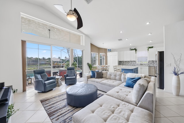 tiled living room with sink, ceiling fan, and high vaulted ceiling