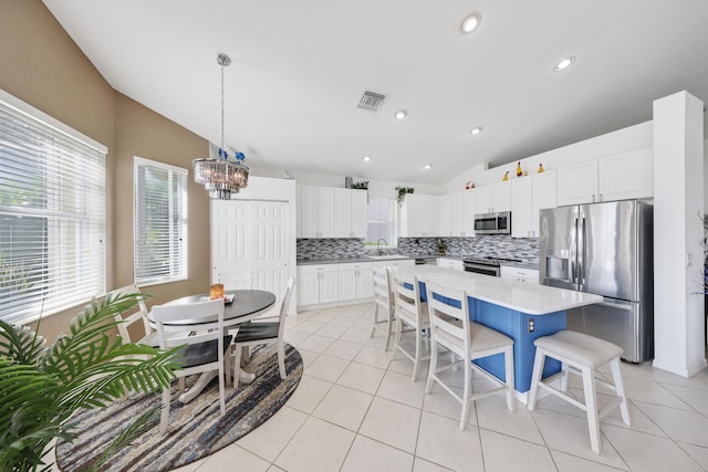 kitchen featuring a center island, white cabinets, backsplash, stainless steel appliances, and lofted ceiling