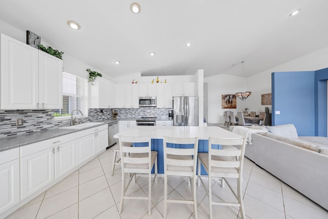 kitchen featuring sink, a kitchen bar, vaulted ceiling, and appliances with stainless steel finishes