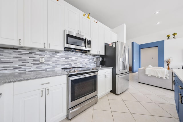 kitchen with light stone countertops, white cabinets, appliances with stainless steel finishes, tasteful backsplash, and light tile patterned floors