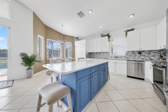 kitchen featuring a center island, appliances with stainless steel finishes, hanging light fixtures, decorative backsplash, and blue cabinets