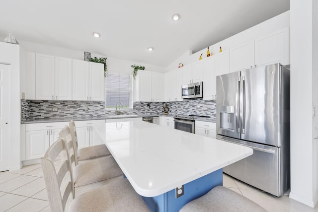 kitchen featuring a center island, a kitchen breakfast bar, sink, white cabinets, and stainless steel appliances