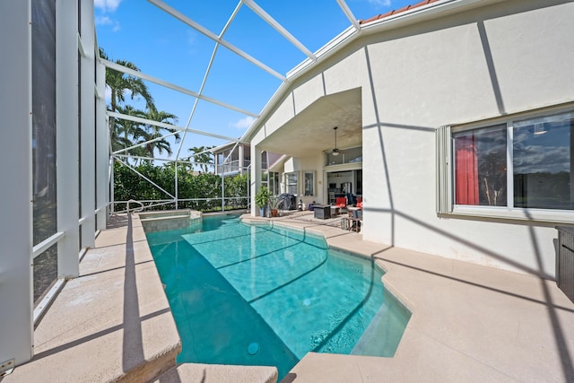 view of pool featuring glass enclosure, a patio, and ceiling fan