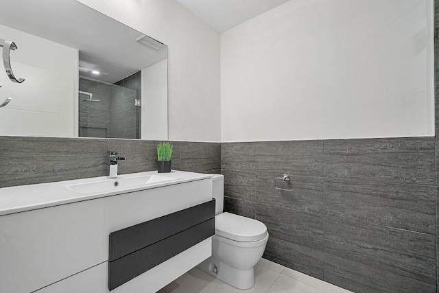 bathroom featuring tile patterned floors, vanity, tile walls, and toilet