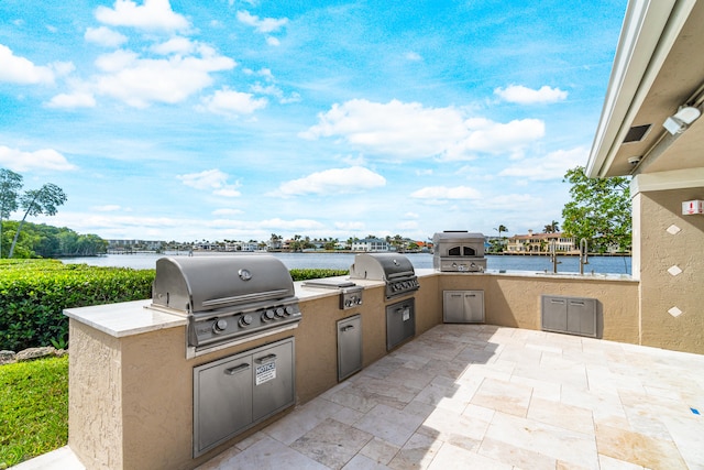 view of patio with an outdoor kitchen, a water view, and grilling area