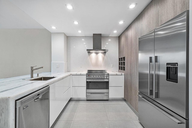 kitchen with wall chimney range hood, sink, light tile patterned floors, appliances with stainless steel finishes, and kitchen peninsula