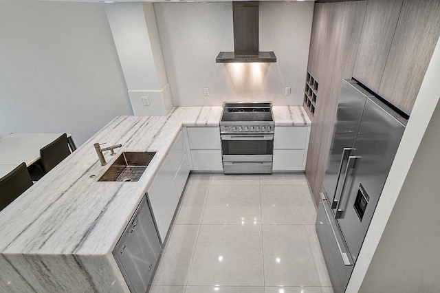 kitchen with a kitchen bar, stainless steel appliances, sink, wall chimney range hood, and white cabinets